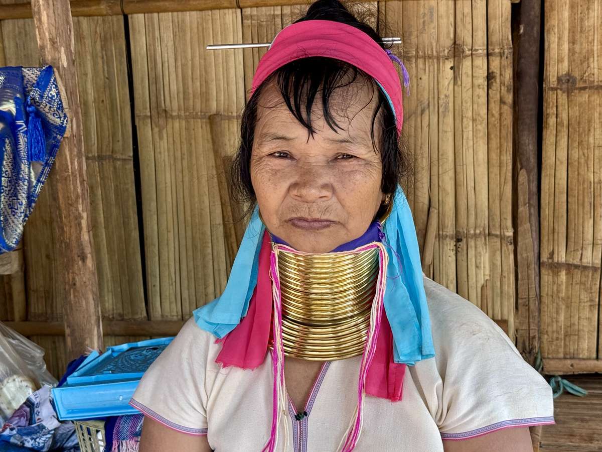 Thailand, Chiang Rai: Eine Frau der Volksgruppe Kayan Lahwi, «Long Neck Karen» genannt, sitzt vor ihrem Haus in einem Dorf nördlich von Chiang Rai. Die Frauen sind für die schweren Messingringe bekannt, die sie um den Hals tragen und die die Illusion eines verlängerten Halses erzeugen. Die Kayan Lahwi, die aus dem Krisenland Myanmar geflohen sind, leben in Thailand als Minderheit. (zu dpa: «Bei den Langhalsfrauen von Chiang Rai: Kultur oder Kommerz?») Foto: Carola Frentzen/dpa +++ dpa-Bildfunk +++